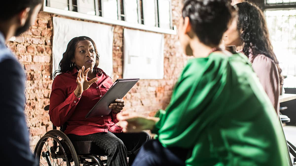 A team meeting with three colleagues attentively listening to their female colleague in a meeting space.