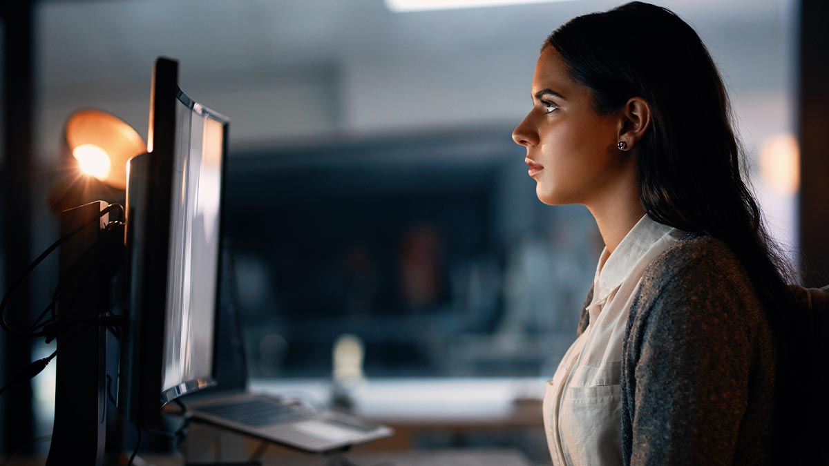 A woman sat at a desk, looking at her computer screen