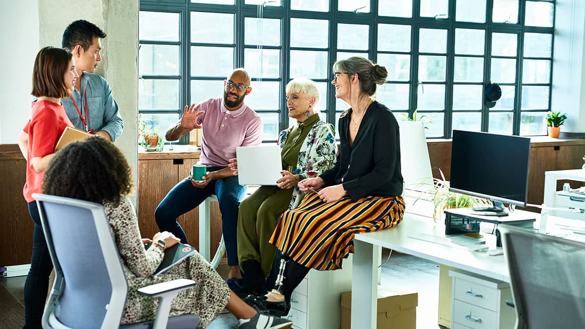 Workers in an office having a discussion gathered at a desk